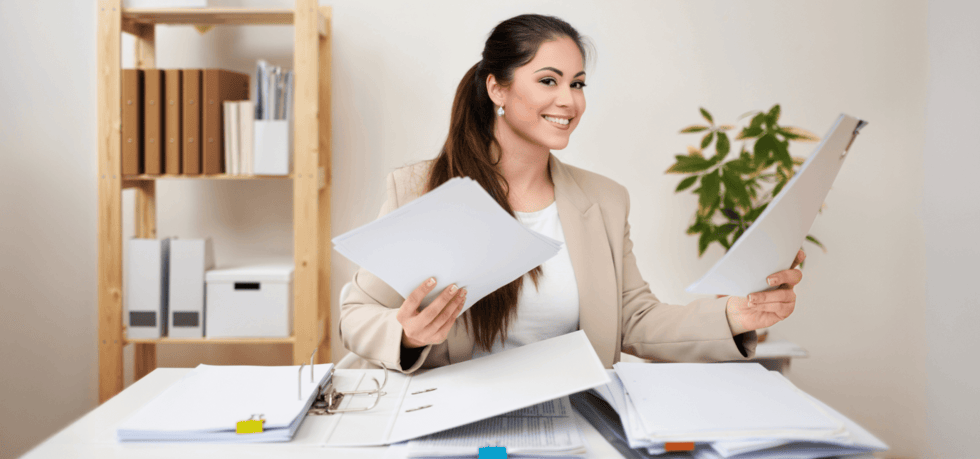 woman sitting at desk holding papers